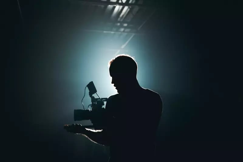 The shadow of a camera man with a glowing light around his frame