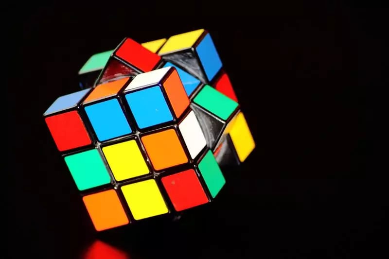 A rubicks cube on its side against a black backdrop