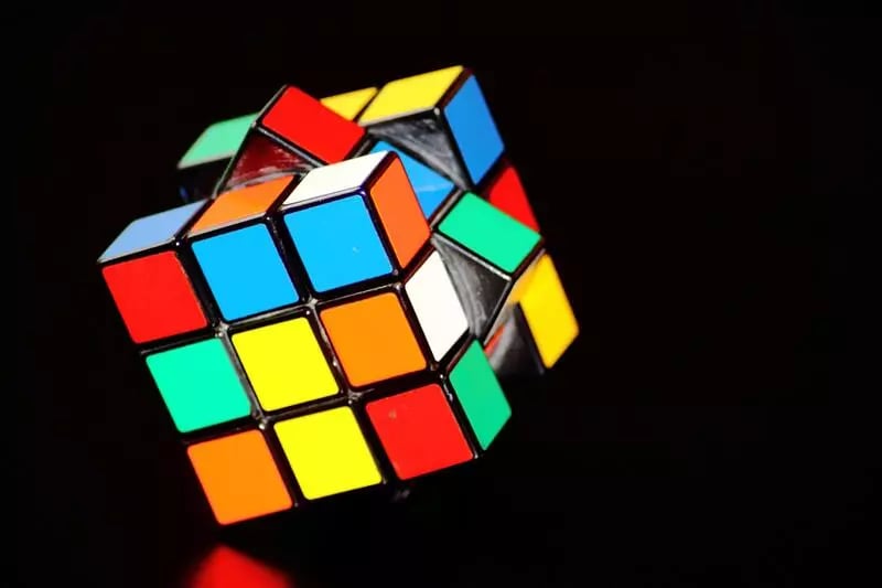 A rubicks cube on its side against a black backdrop