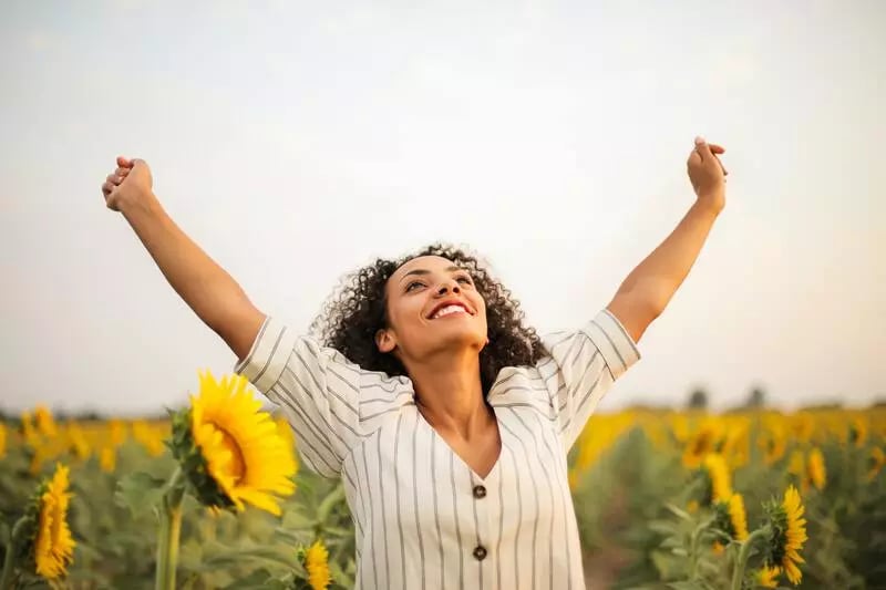 Woman in field of sunflowers smiling, showcasing emotion in b2b marketing