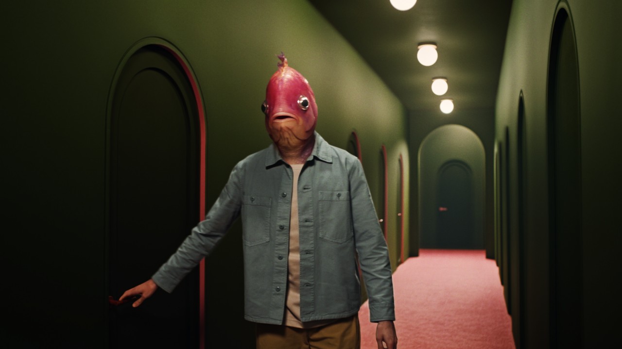 A fish-headed man walking down a green Kubrick-esque corridor