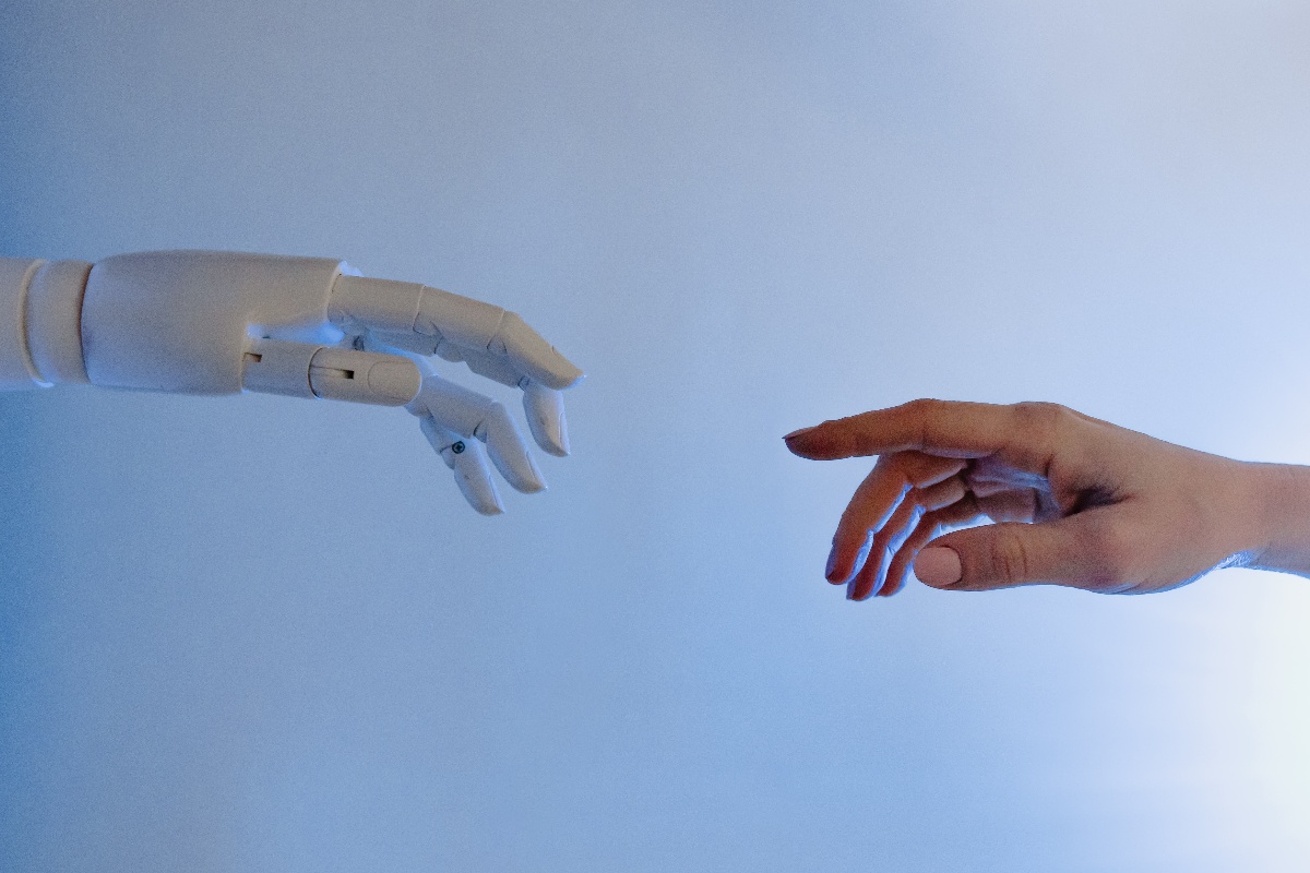 A robot hand and a human hand reach for each other to represent the relationship between AI and Marketing teams