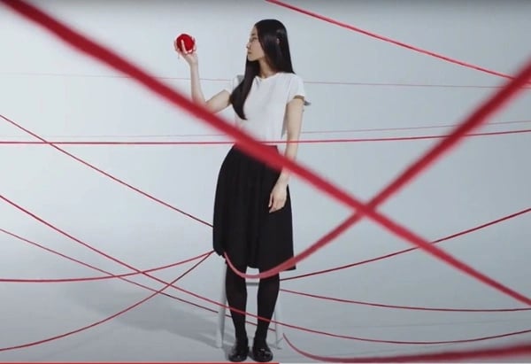 A woman holding a ball of red string, an example of one of the best recruiting videos to date.